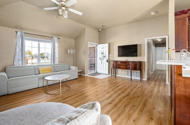 living room with ceiling fan, light wood-type flooring, and vaulted ceiling