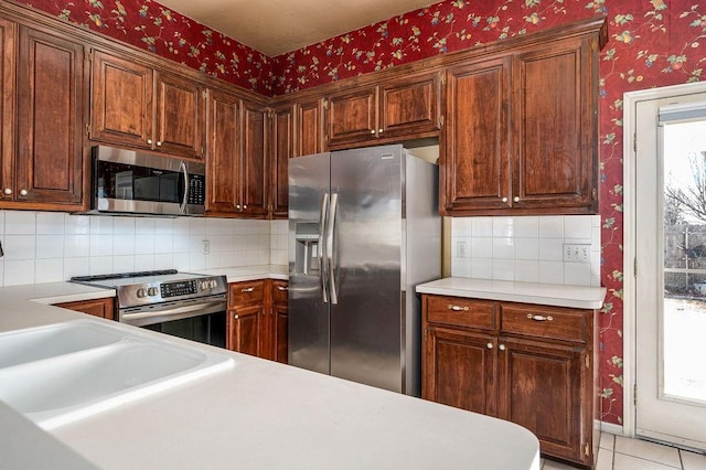 kitchen with light tile patterned floors, tasteful backsplash, and appliances with stainless steel finishes