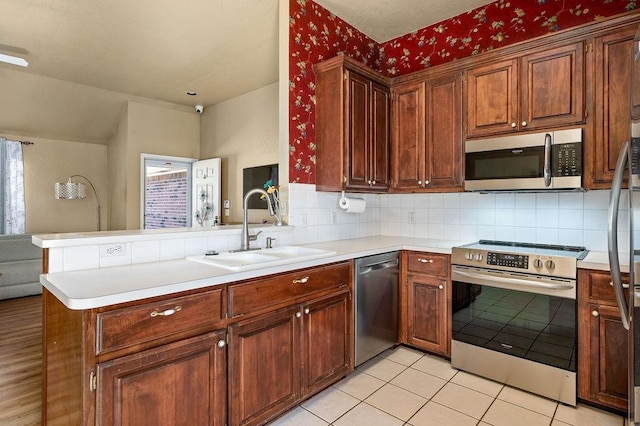 kitchen with stainless steel appliances, sink, backsplash, and kitchen peninsula