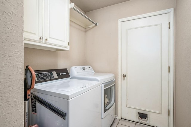 washroom with cabinets, washing machine and dryer, and light tile patterned floors