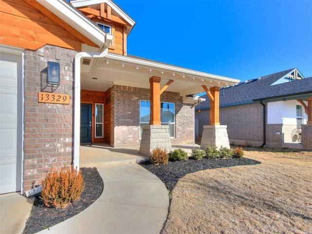 view of exterior entry featuring covered porch and a garage