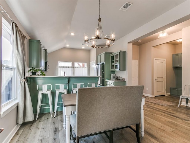 dining area featuring light hardwood / wood-style flooring, lofted ceiling, and a chandelier