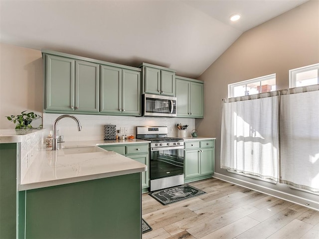 kitchen featuring lofted ceiling, tasteful backsplash, sink, appliances with stainless steel finishes, and green cabinetry