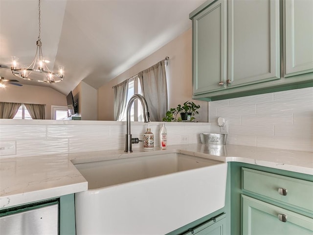 interior details featuring hanging light fixtures, light stone countertops, sink, and green cabinetry