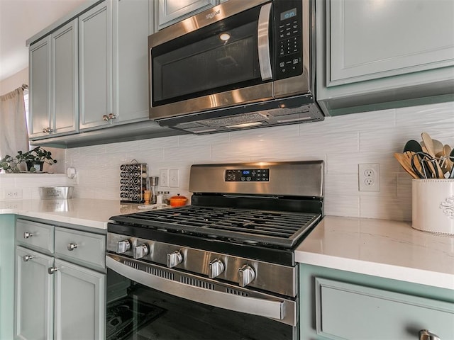 kitchen with backsplash, gray cabinetry, and stainless steel appliances