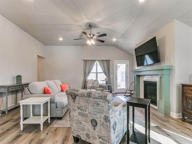 living room with vaulted ceiling, ceiling fan, light hardwood / wood-style floors, and a fireplace