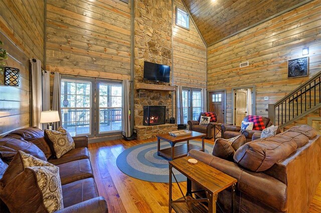 living room with wood-type flooring, high vaulted ceiling, a healthy amount of sunlight, and a fireplace