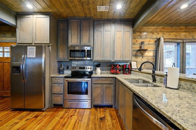 kitchen with light stone counters, sink, wood ceiling, and appliances with stainless steel finishes