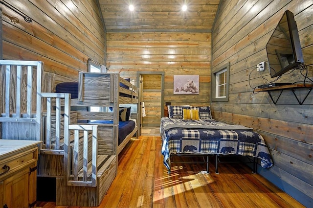 bedroom with a high ceiling, wood-type flooring, and wood walls