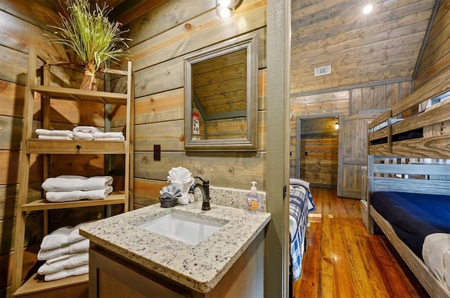 bathroom with vanity, hardwood / wood-style floors, and wooden walls