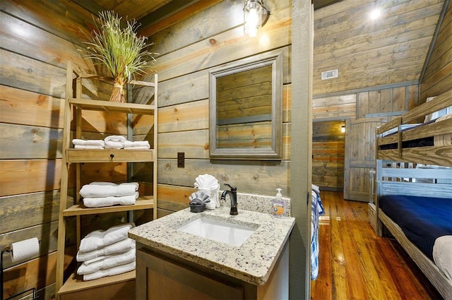 bathroom featuring vanity, hardwood / wood-style flooring, and wood walls