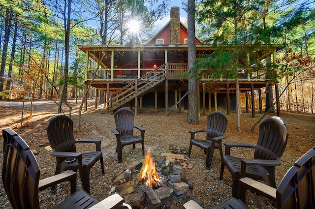 back of property with a wooden deck and a fire pit