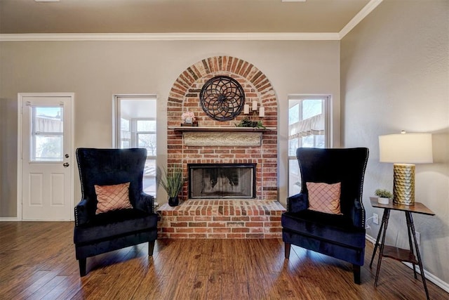 living area with a brick fireplace, hardwood / wood-style floors, and crown molding