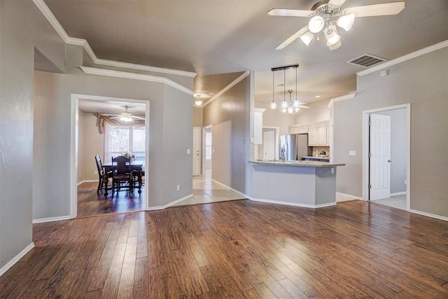 interior space featuring white cabinetry, ornamental molding, kitchen peninsula, stainless steel fridge with ice dispenser, and dark hardwood / wood-style floors