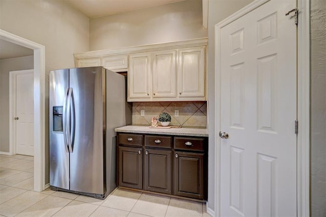 kitchen with light tile patterned floors, decorative backsplash, dark brown cabinets, and stainless steel fridge with ice dispenser