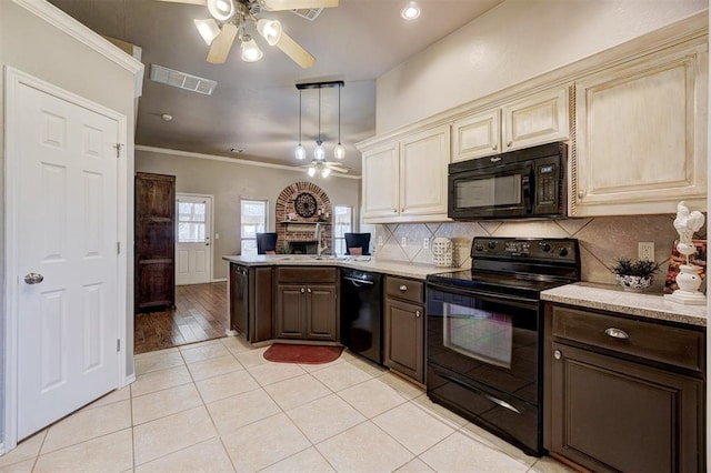 kitchen featuring tasteful backsplash, cream cabinetry, black appliances, and dark brown cabinets