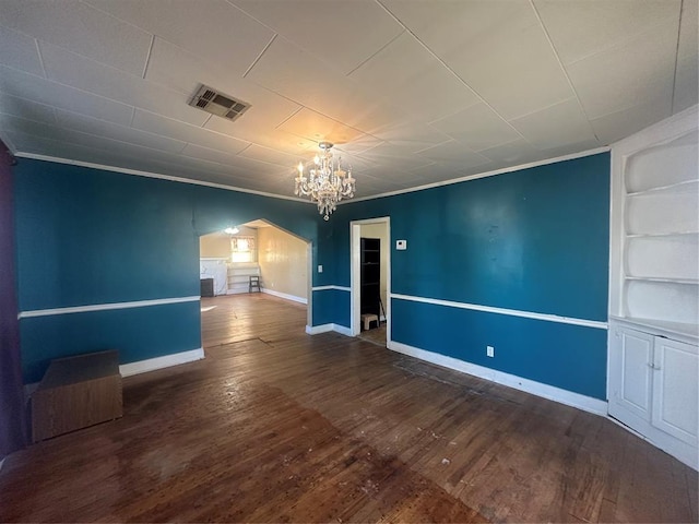 unfurnished room featuring ornamental molding, built in features, a chandelier, and wood-type flooring