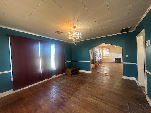 spare room with hardwood / wood-style floors, plenty of natural light, crown molding, and a chandelier