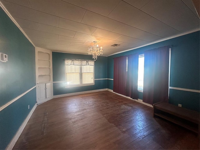 spare room featuring built in shelves, an inviting chandelier, and hardwood / wood-style floors