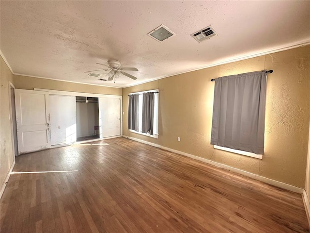 unfurnished bedroom with hardwood / wood-style floors, a closet, ceiling fan, ornamental molding, and a textured ceiling