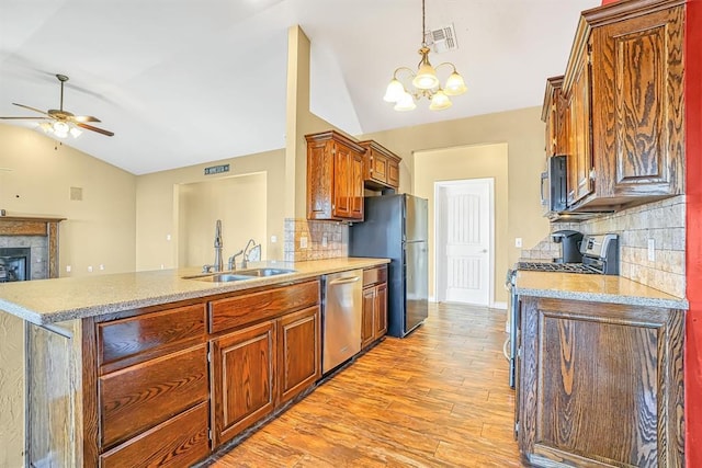 kitchen with appliances with stainless steel finishes, decorative backsplash, a fireplace, and sink