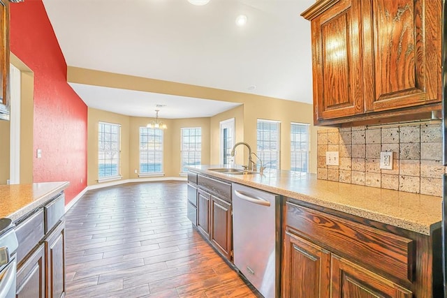 kitchen featuring tasteful backsplash, a notable chandelier, dark wood-type flooring, stainless steel dishwasher, and sink