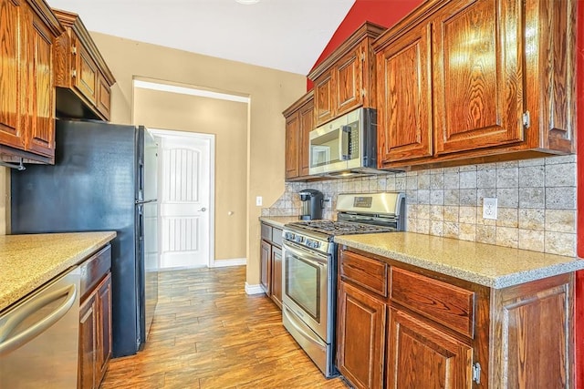 kitchen featuring backsplash, stainless steel appliances, and light wood-type flooring