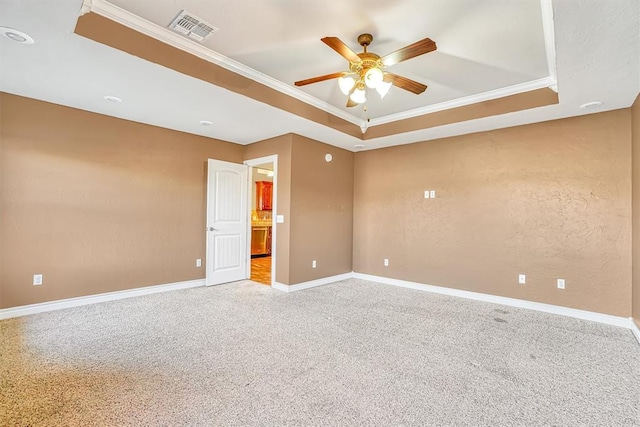 carpeted empty room with ceiling fan, a tray ceiling, and ornamental molding