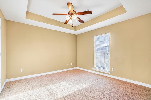 carpeted empty room featuring ceiling fan and a tray ceiling