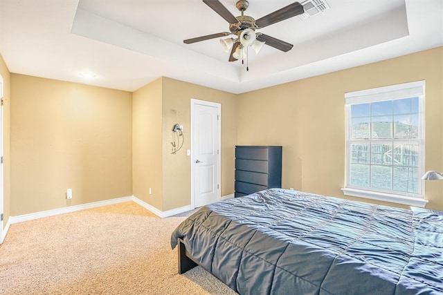 bedroom with ceiling fan, carpet floors, and a tray ceiling