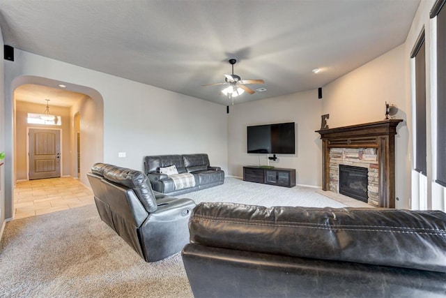 living room featuring a fireplace, ceiling fan, and light carpet