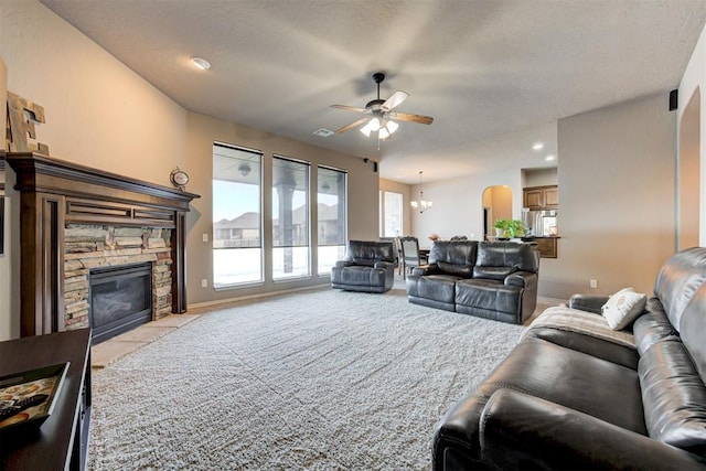 carpeted living room featuring a textured ceiling, ceiling fan with notable chandelier, and a fireplace