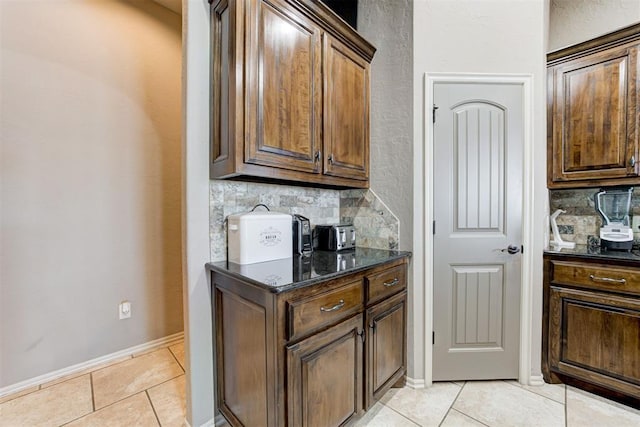 kitchen featuring light tile patterned floors, tasteful backsplash, and dark stone counters