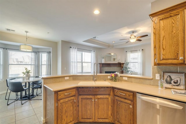 kitchen with kitchen peninsula, dishwasher, light tile patterned floors, ceiling fan, and sink