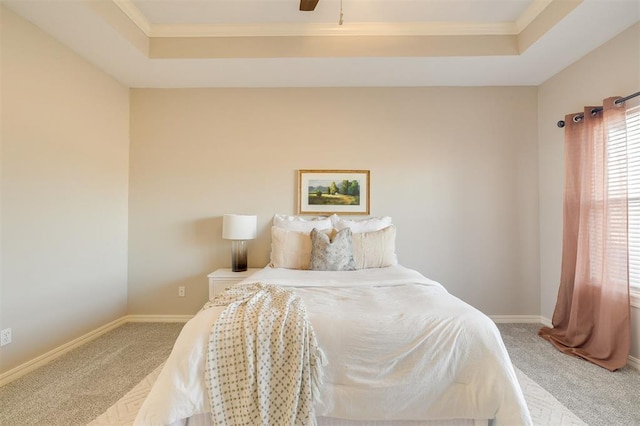 carpeted bedroom with a raised ceiling, ceiling fan, and crown molding