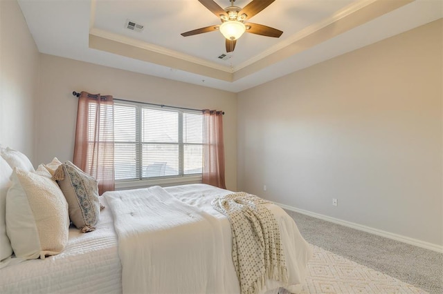 carpeted bedroom featuring ceiling fan, a tray ceiling, and ornamental molding