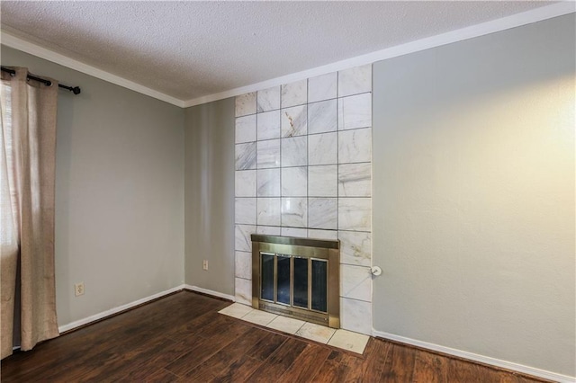 unfurnished living room featuring a tile fireplace, a textured ceiling, hardwood / wood-style floors, and crown molding