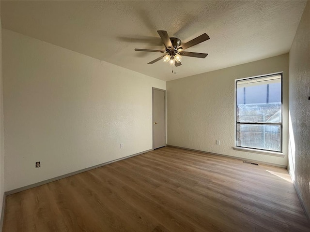 unfurnished room with a textured ceiling, ceiling fan, and wood-type flooring