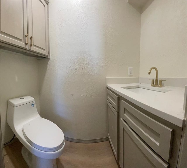 bathroom with toilet, vanity, and hardwood / wood-style floors