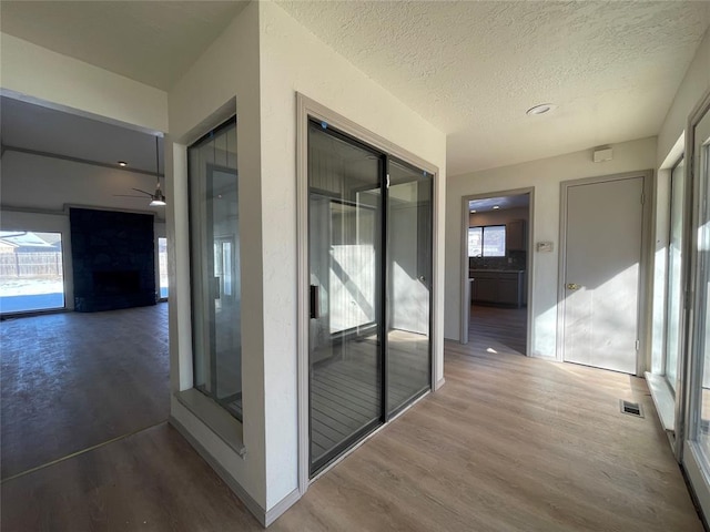 hall with a textured ceiling and wood-type flooring