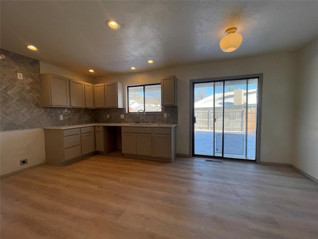 kitchen with sink, light hardwood / wood-style floors, and backsplash