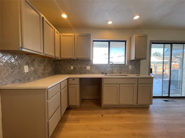 kitchen featuring sink, light wood-type flooring, and backsplash