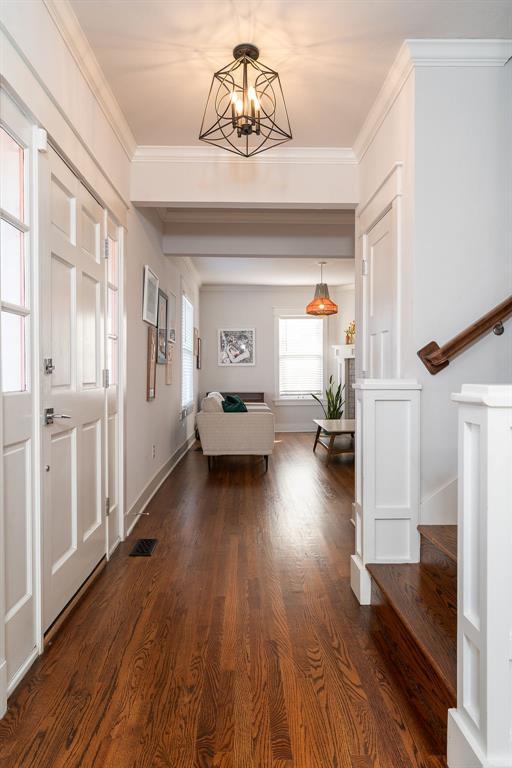 hallway featuring dark wood-type flooring, ornamental molding, and a chandelier