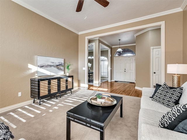 living room with ceiling fan, ornamental molding, and carpet