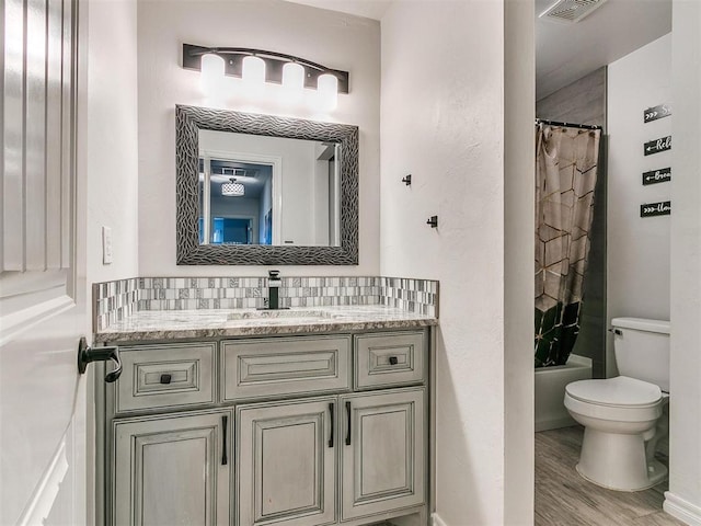 full bathroom with hardwood / wood-style floors, vanity, shower / tub combo, tasteful backsplash, and toilet