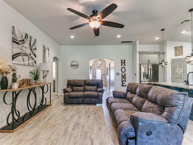 living room with ceiling fan, sink, and light wood-type flooring