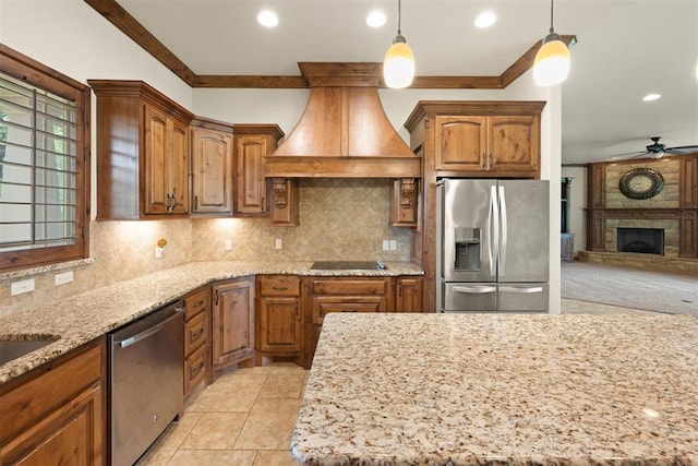 kitchen featuring appliances with stainless steel finishes, ceiling fan, custom exhaust hood, pendant lighting, and a stone fireplace