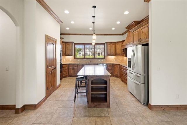 kitchen with decorative light fixtures, a center island, a kitchen bar, crown molding, and appliances with stainless steel finishes