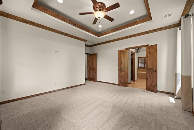 unfurnished room with ceiling fan, light carpet, ornamental molding, and a raised ceiling