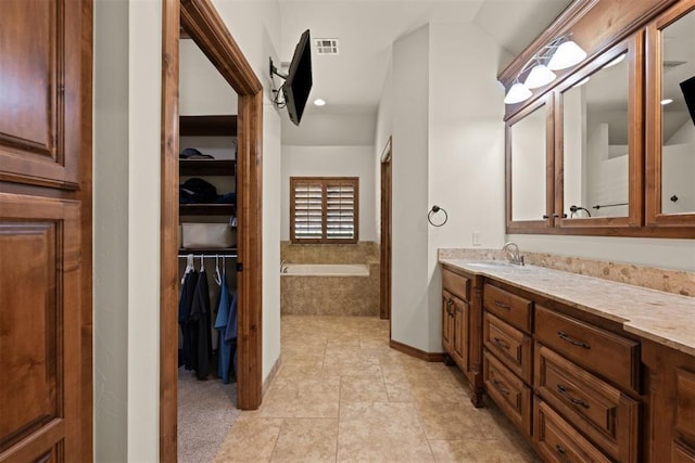 bathroom with tiled tub, tile patterned floors, and vanity